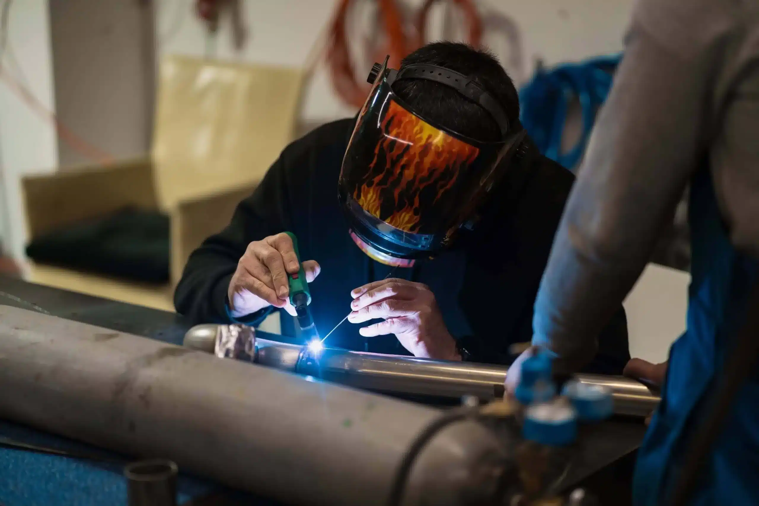 Welder using an argon welding machine to work on a metal pipe in a workshop