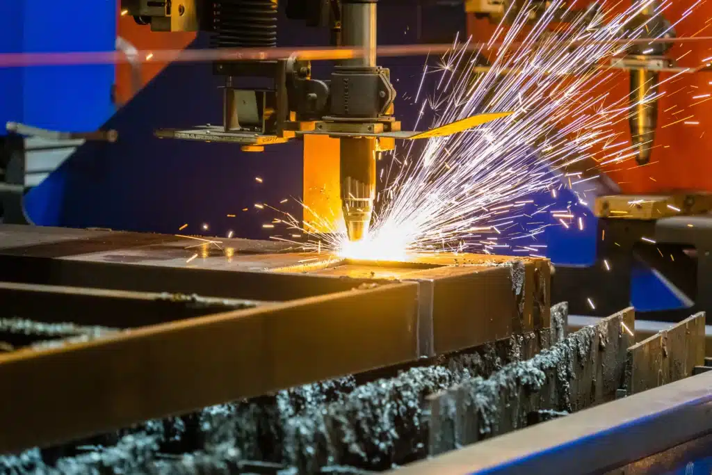 Close-up of an industrial steel cutting machine cutting thick metal plate with bright sparks in a fabrication workshop.